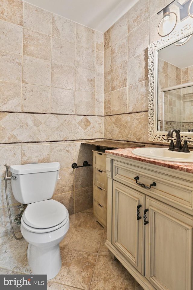 bathroom with vanity, toilet, tile walls, and a stall shower