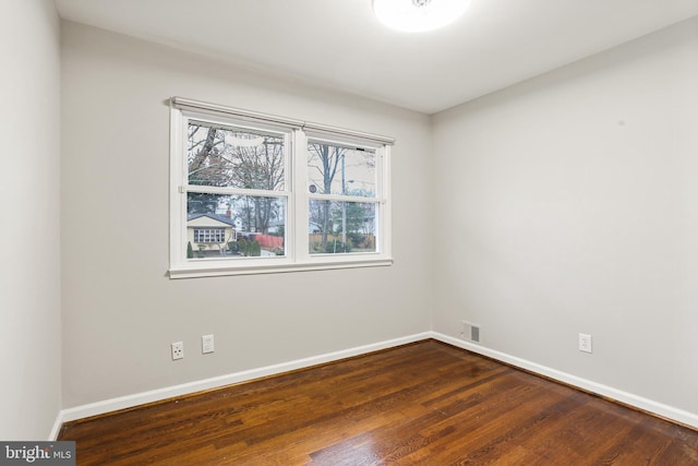 unfurnished room with visible vents, baseboards, and dark wood-style floors