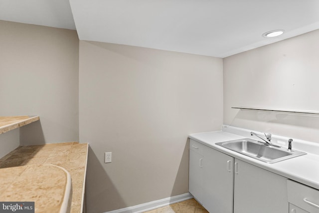 clothes washing area featuring baseboards and a sink