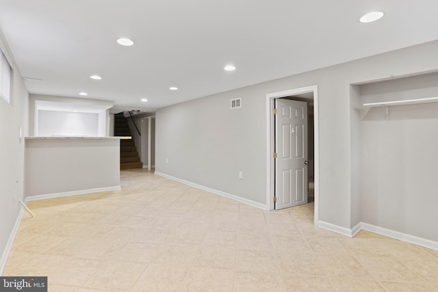 finished below grade area with recessed lighting, visible vents, baseboards, and stairway