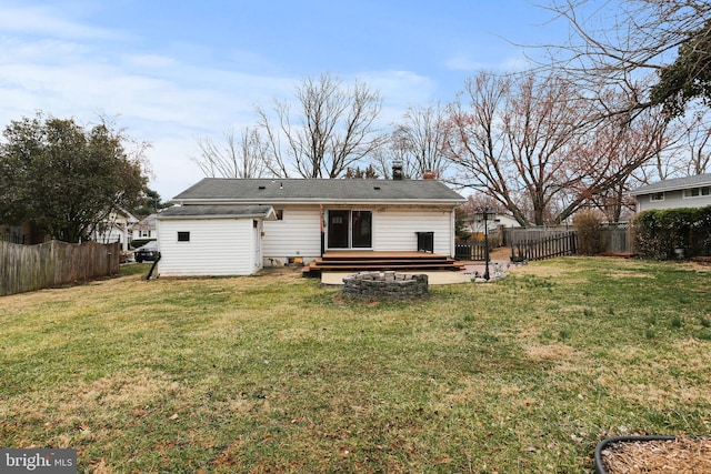 rear view of property featuring a lawn, a wooden deck, and a fenced backyard