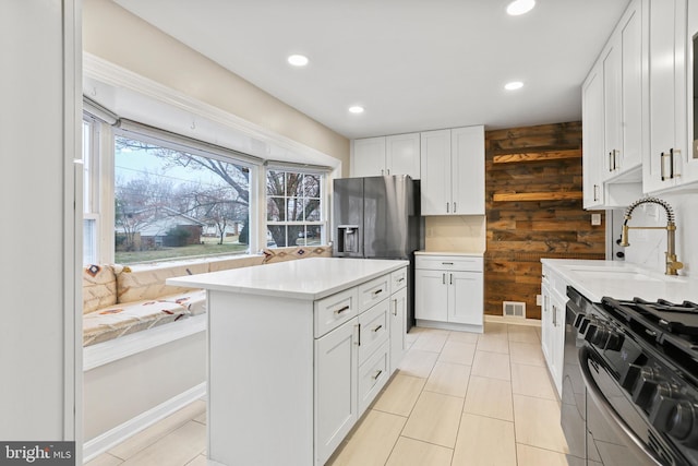 kitchen featuring wooden walls, white cabinetry, light countertops, and gas range oven