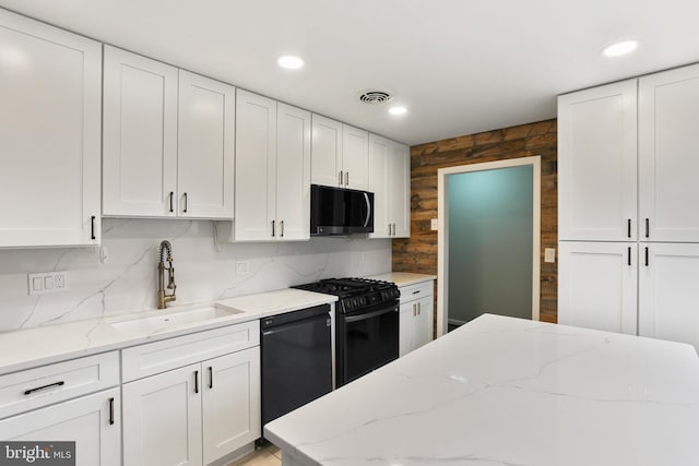 kitchen with visible vents, black appliances, a sink, white cabinets, and light stone countertops