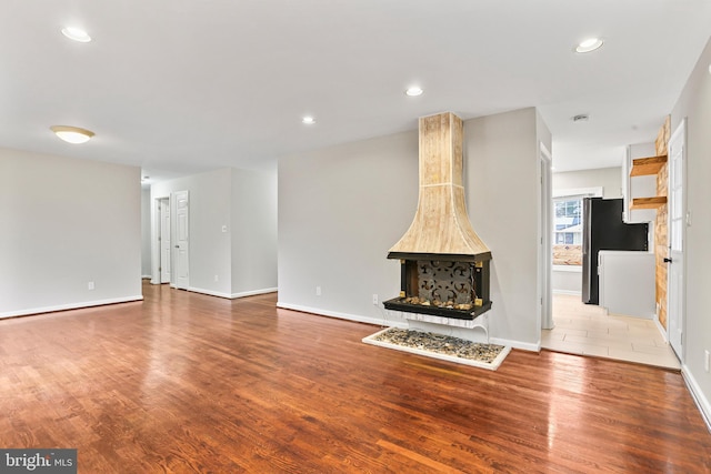 unfurnished living room featuring recessed lighting, wood finished floors, and baseboards