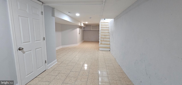 finished below grade area featuring visible vents, baseboards, and stairway