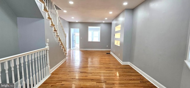 hallway featuring stairway, recessed lighting, wood finished floors, and baseboards