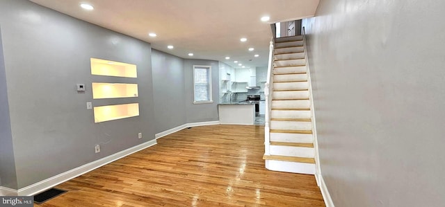 hall featuring stairway, baseboards, visible vents, and wood finished floors