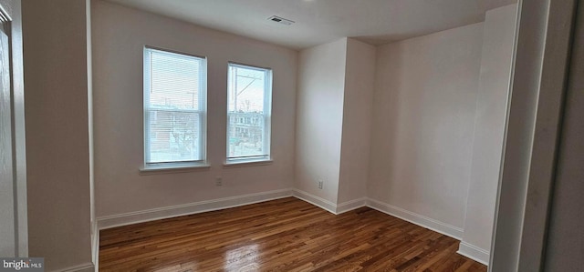 spare room featuring visible vents, baseboards, and dark wood-style flooring