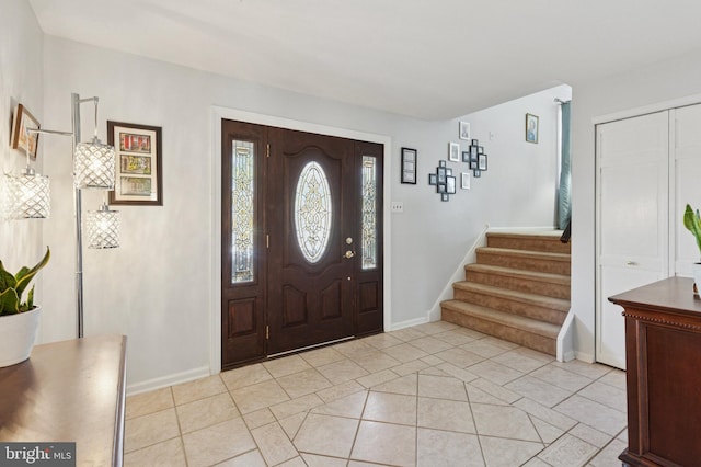 entryway with light tile patterned floors, stairway, and baseboards