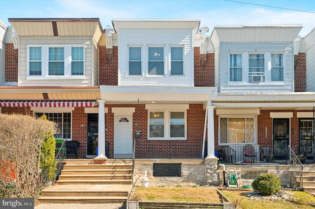 multi unit property featuring brick siding and a porch