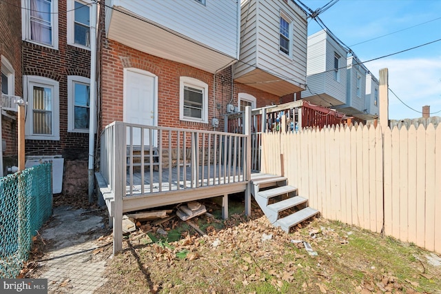 exterior space with a wooden deck, brick siding, and fence