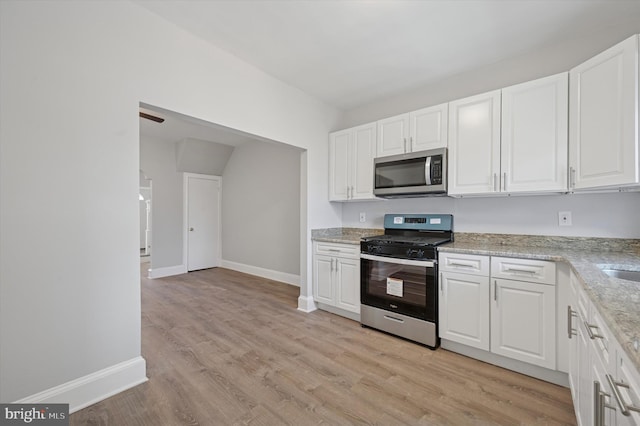 kitchen with light wood-type flooring, stainless steel appliances, and white cabinets