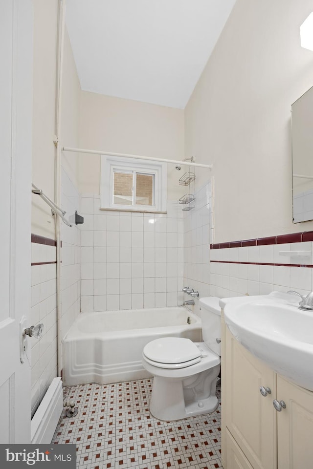 full bathroom featuring vanity, a wainscoted wall, bathtub / shower combination, tile walls, and toilet