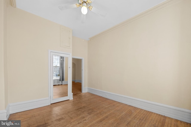 empty room featuring baseboards, light wood-style floors, a ceiling fan, and crown molding