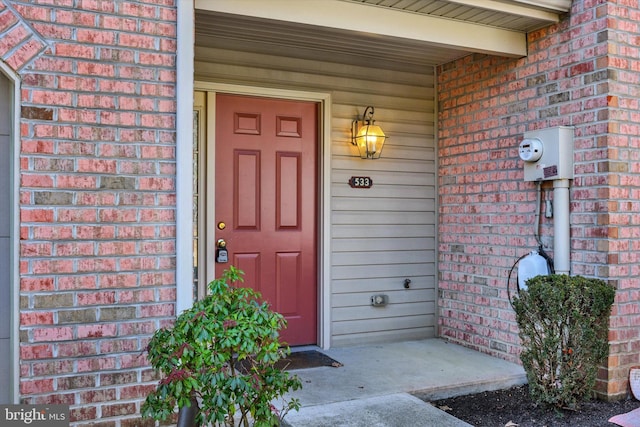 doorway to property with brick siding and a porch