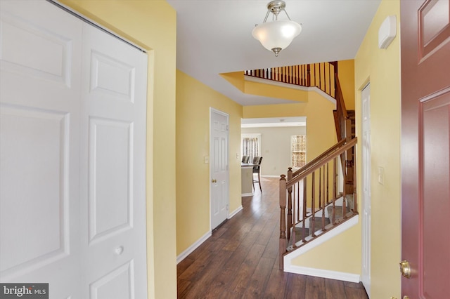 corridor with stairs, baseboards, and dark wood-style flooring