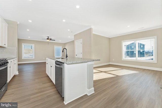 kitchen with a sink, open floor plan, stainless steel appliances, light wood finished floors, and baseboards