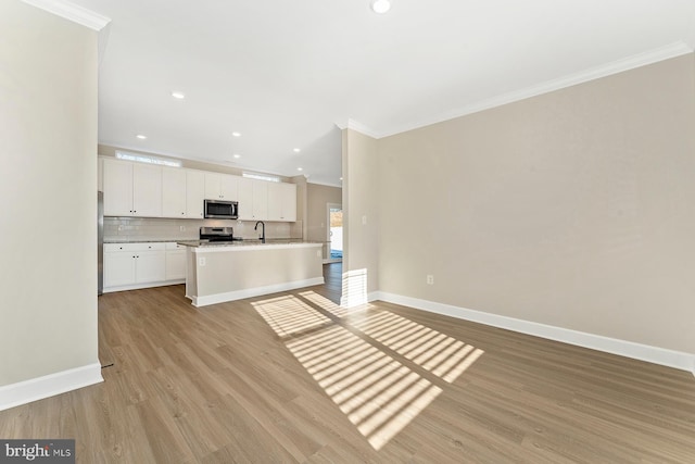 unfurnished living room featuring recessed lighting, baseboards, ornamental molding, and light wood finished floors