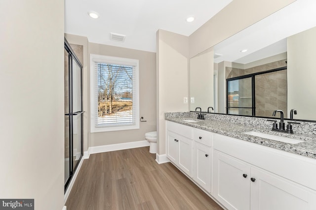 full bathroom with a sink, visible vents, wood finished floors, and a stall shower