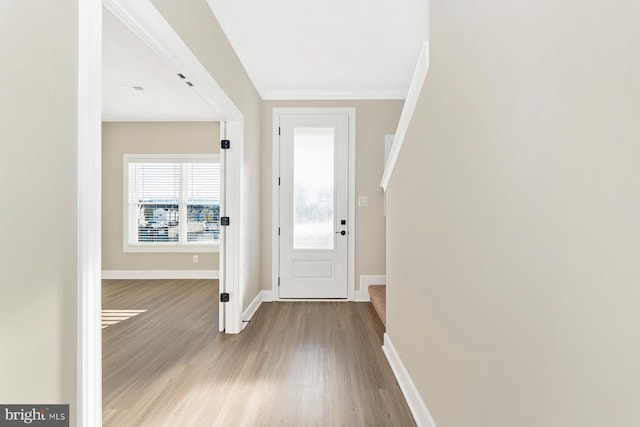 entrance foyer with baseboards, wood finished floors, ornamental molding, and stairs