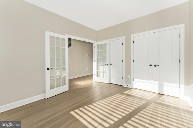 unfurnished bedroom with french doors, baseboards, and wood finished floors