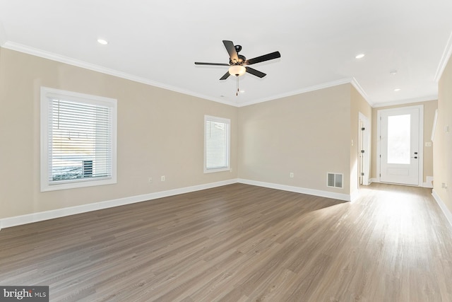 unfurnished living room with visible vents, crown molding, baseboards, and wood finished floors