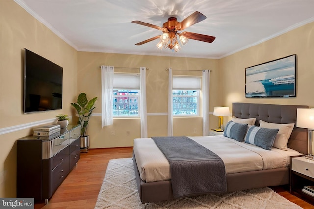 bedroom featuring a ceiling fan, light wood-style floors, and ornamental molding