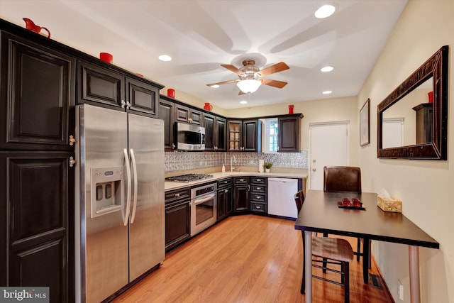 kitchen with light countertops, decorative backsplash, light wood-style flooring, stainless steel appliances, and a sink