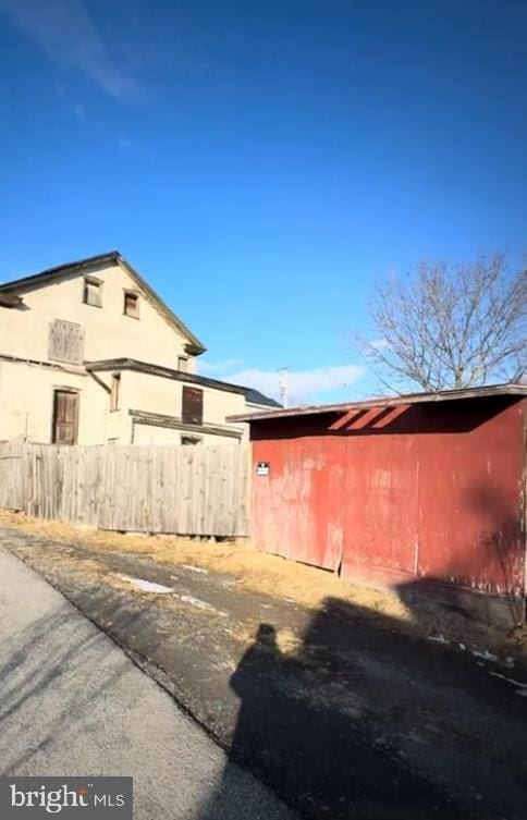 view of side of property featuring stucco siding, an outbuilding, and fence