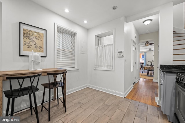 corridor with stairs, recessed lighting, baseboards, and light wood finished floors