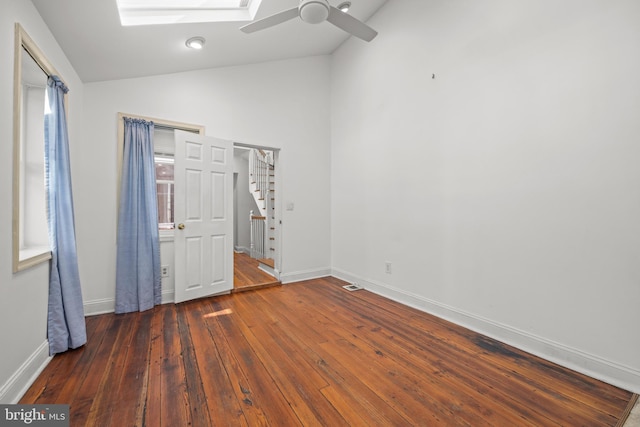 unfurnished bedroom with lofted ceiling with skylight, ceiling fan, baseboards, and hardwood / wood-style floors