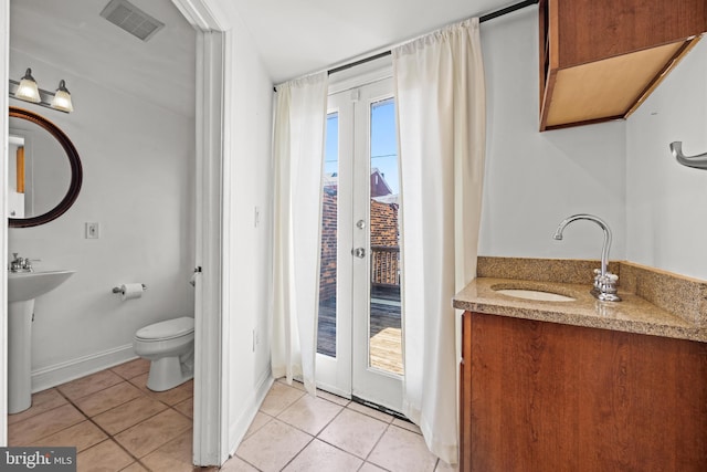 bathroom featuring tile patterned floors, visible vents, toilet, a sink, and french doors