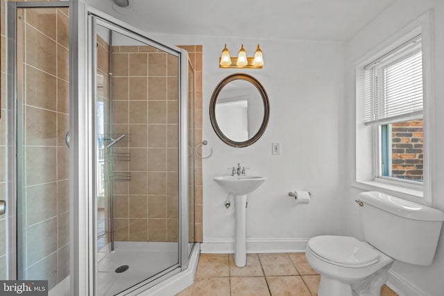 bathroom with baseboards, toilet, a stall shower, and tile patterned flooring