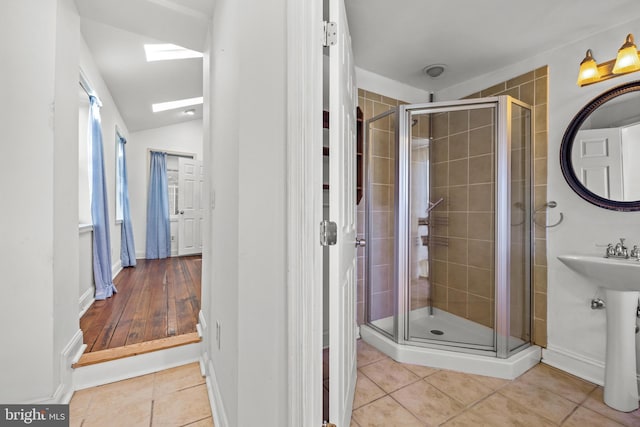 bathroom featuring tile patterned flooring, a shower stall, and vaulted ceiling