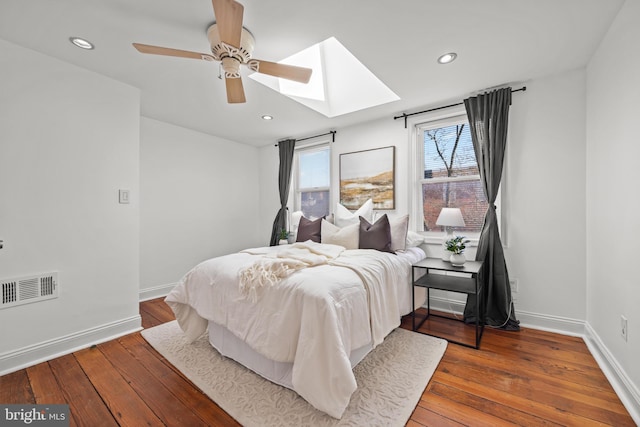 bedroom with hardwood / wood-style floors, baseboards, visible vents, a skylight, and recessed lighting