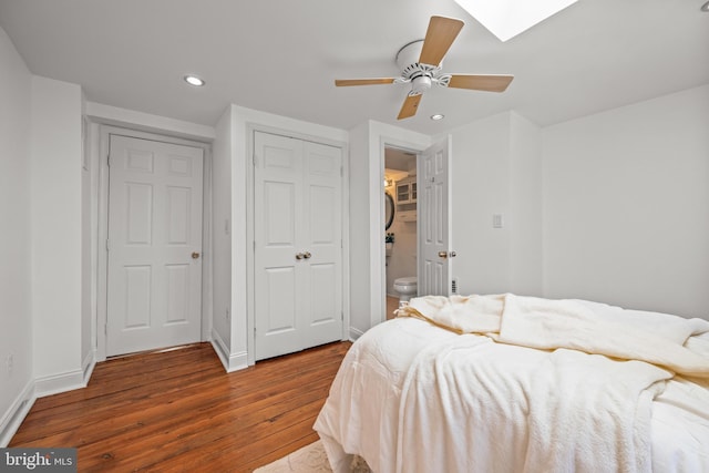 bedroom featuring recessed lighting, a skylight, baseboards, and wood finished floors