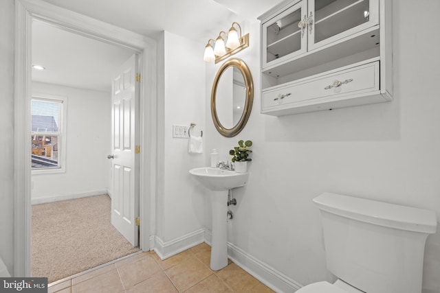 bathroom with baseboards, toilet, and tile patterned flooring