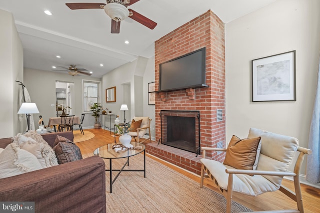 living area with recessed lighting, light wood-type flooring, and a brick fireplace