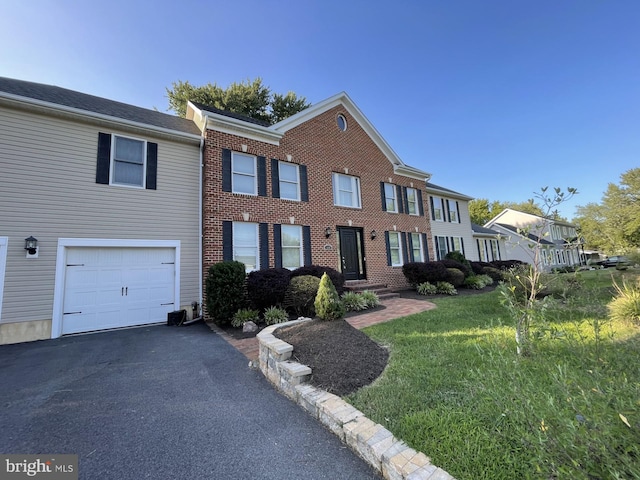 view of front of home featuring a front lawn, an attached garage, brick siding, and driveway