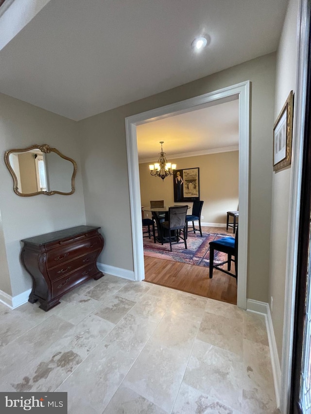 hallway featuring baseboards and an inviting chandelier