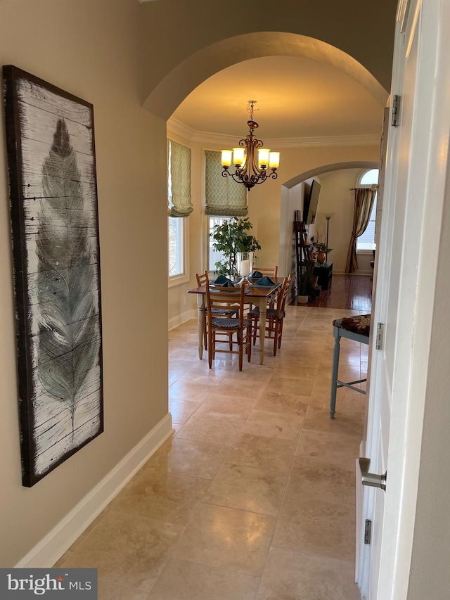 dining room with crown molding, arched walkways, and a chandelier
