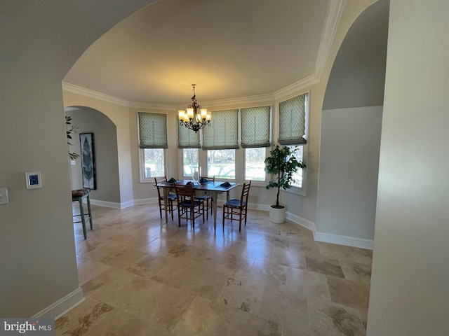 dining space featuring arched walkways, baseboards, a chandelier, and crown molding