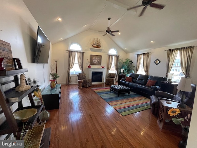 living room featuring ceiling fan, high vaulted ceiling, wood finished floors, and a fireplace