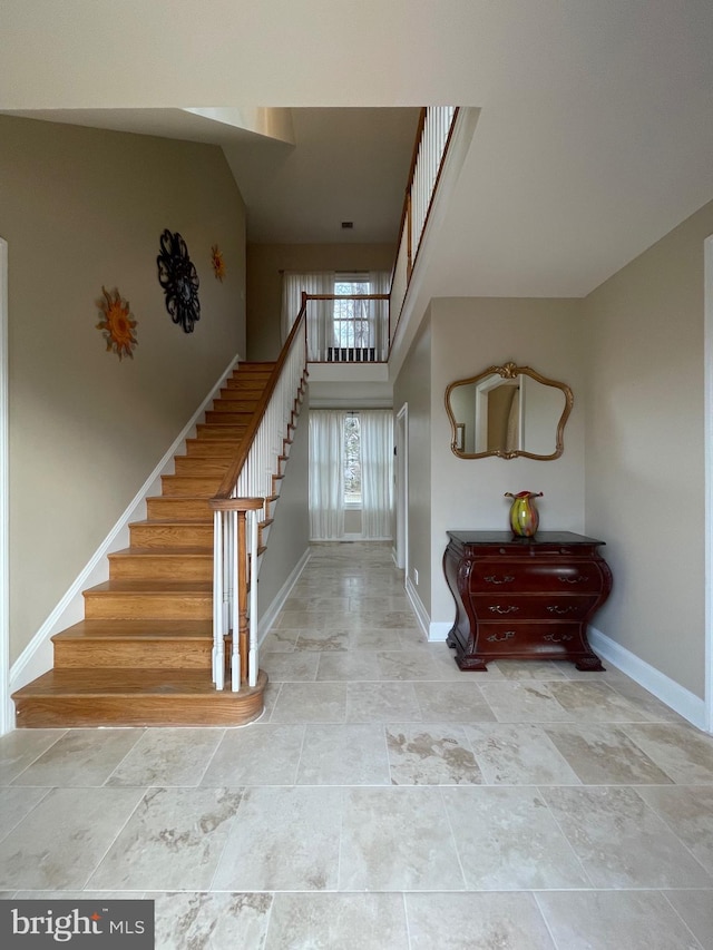foyer entrance with a high ceiling, baseboards, and stairs