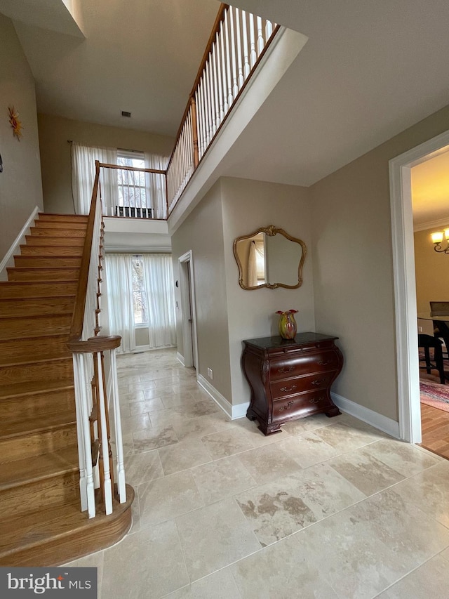 interior space with stairs, baseboards, visible vents, a towering ceiling, and an inviting chandelier