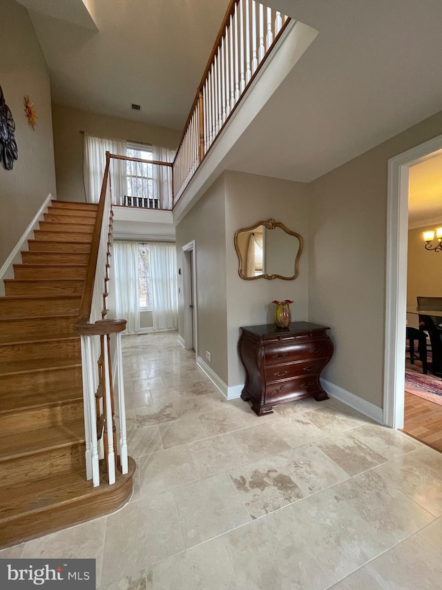foyer with visible vents, baseboards, a towering ceiling, stairway, and a notable chandelier