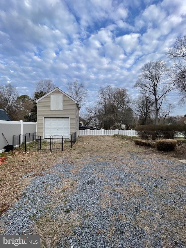 view of yard featuring driveway, a garage, fence, and an outdoor structure