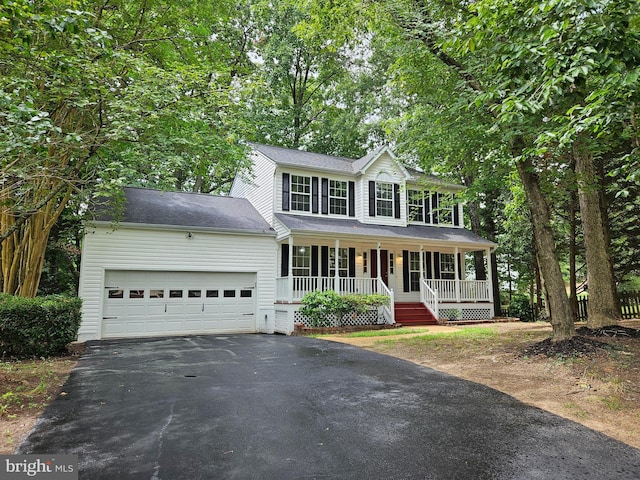 colonial house with covered porch, driveway, and an attached garage