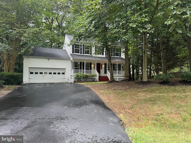 colonial house featuring aphalt driveway, a porch, and an attached garage