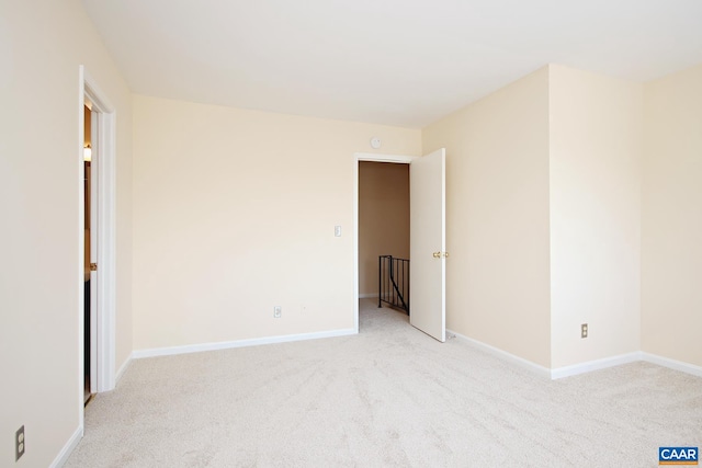 spare room with baseboards and light carpet